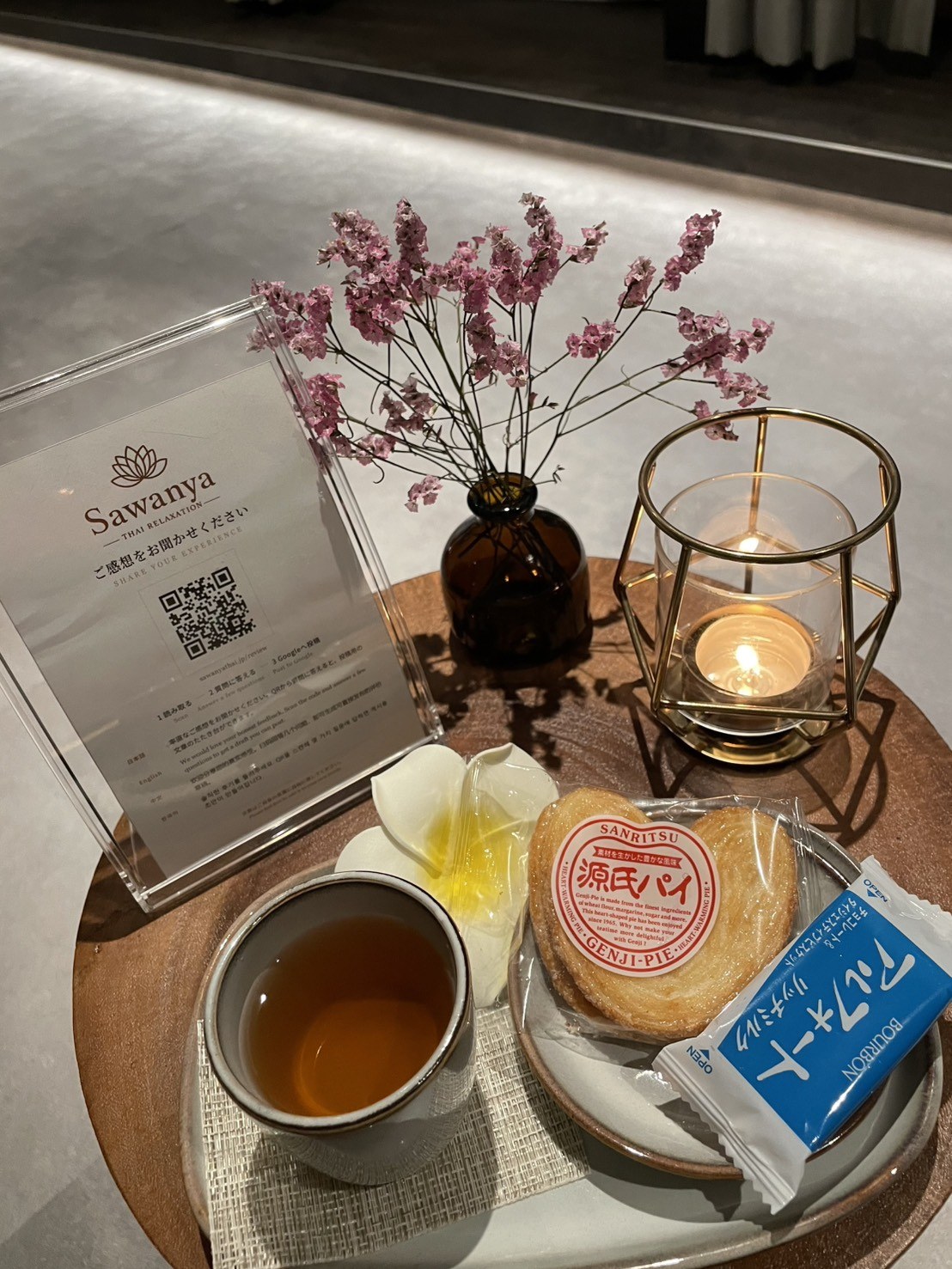 Tea and sweets with flowers and a candle